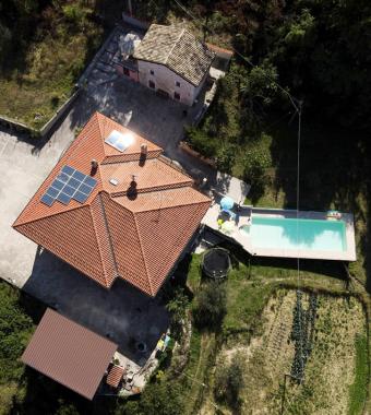 Vista aerea di una casa con piscina, pannelli solari e giardino.