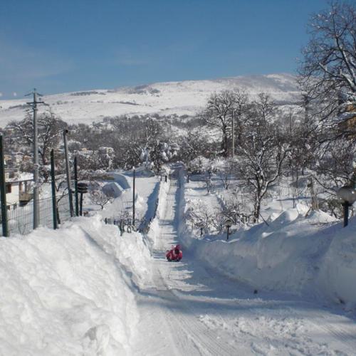 Strada innevata con persona che slitta, paesaggio montano invernale.