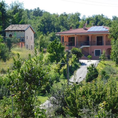 Casa in campagna con pannelli solari, circondata da verde e alberi.